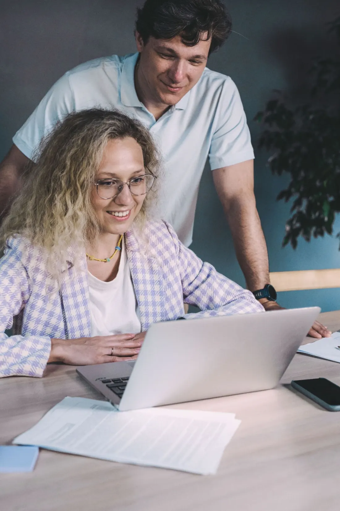 Two colleagues at a laptop, one smiling at what they are building